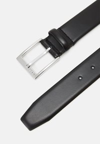 Ceinture en cuir noir avec une boucle rectangulaire en argent brillant, texture lisse, extrémité effilée et plusieurs trous d'ajustement le long de la sangle.