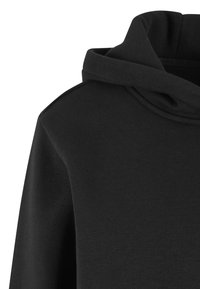 Czarna bluza z kapturem na luźno oraz widocznym szwem na ramieniu, prezentująca miękki, teksturowany materiał.