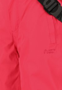 Lysepink vandtætte bukser med en glat tekstur, sidelommer og et lille broderet "NORTH BEND" logo nær lommen.
