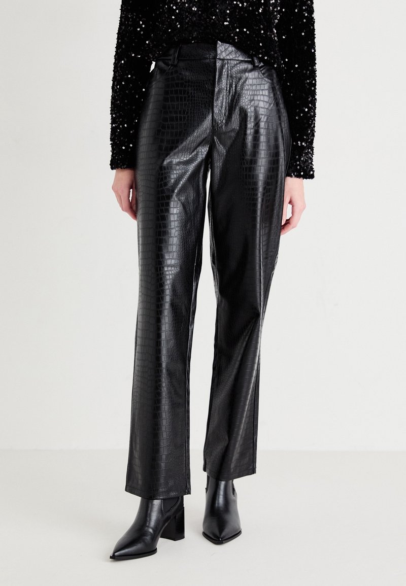 Pantalons en faux cuir noir avec une texture imprimée crocodile. Design à jambe droite et taille haute, associés à des bottines noires.