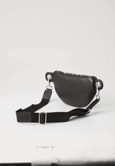 Sac en cuir noir en bandoulière au design arrondi, matériel en acier inoxydable, et une sangle texturée arborant le nom de la marque "VOLTAIRE."