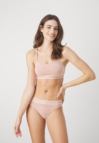 Light pink bralette and matching panties with small patterned details. Soft fabric, thin straps, and white elastic waistband.