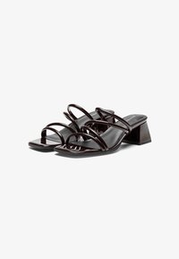 Mules à talons hauts brillantes marron, présentant de multiples fines lanières, une forme de bout carré et un large talon bloc pour le soutien.