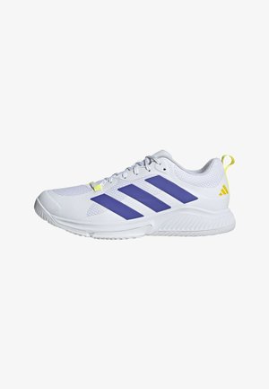 Zapatilla deportiva blanca con rayas azules, lengüeta amarilla en el talón, parte superior de malla y suela texturizada, mostrada desde el lado exterior.