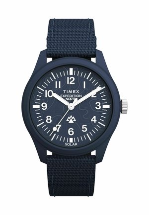 Montre Timex Expedition avec un strap en nylon bleu marine, un cadran rond, des marqueurs d'heure blancs et une fonctionnalité solaire avec des motifs texturés sur le cadran.