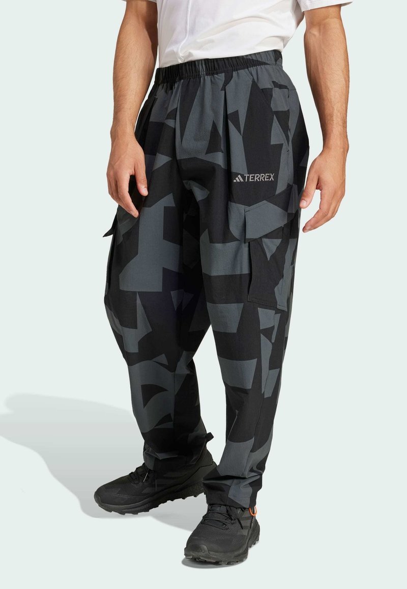 Zwarte en grijze cargo broeken met een geometrisch patroon, voorzien van een elastische tailleband, zijzakken en het "TERREX" logo op de linker dij.