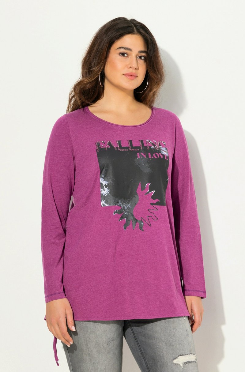 Langes lila T-Shirt mit langen Ärmeln, das einen schwarzen Grafikdruck mit dem Text "FALLING IN LOVE" und einem Sonnenstrahlendesign zeigt. Weiches Material mit lockerer Passform.