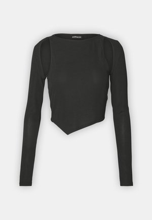 Black long-sleeve crop top made of ribbed fabric, featuring a round neckline and an asymmetrical hemline with cut-out shoulder details.