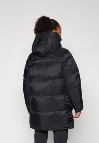 Black puffer coat with a high collar and hood. Features a quilted design with horizontal stitching and a mid-length cut. Smooth texture.