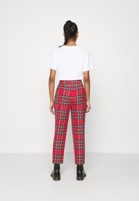 Röda rutiga byxor med svarta och gröna ränder, hög midja och raka ben. Matchas med en vit t-shirt med kort ärm och svarta stövlar.