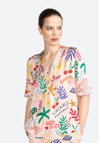 Kortærmet bluse med V-hals i lyserød stof, prydet med et flerfarvet ferietema-print med blomster, sol og tropiske elementer.