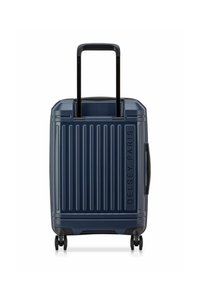 Maleta rígida de color navy con estrías verticales, asa negra retráctil y cuatro ruedas para facilitar el movimiento. Presenta el logo emblema "Delsey Paris".