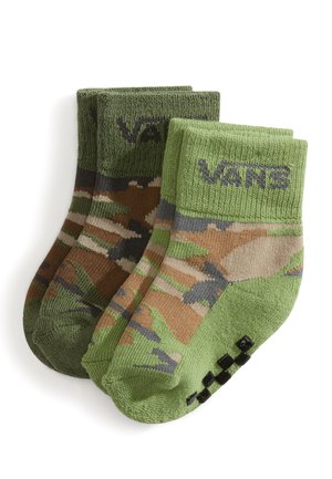 Zwei Paare Vans-Socken mit grünem Tarnmuster und schwarzen Griffpunkten an den Sohlen, gefaltet und auf weißem Hintergrund gestapelt.