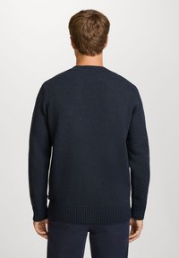 Marineblå strikkegenser med strukturert stoff, lange ermer, ribbestrikket kant nederst og ved ermene, samt rund hals.