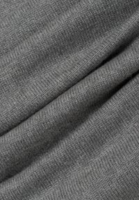 Grau gestrickter Stoff mit einer weichen Textur, der eine glatte Oberfläche und leichte Elastizität aufweist, gefaltet, um seine Dicke und das Muster der Webart zu zeigen.