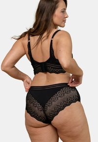 Soutien-gorge en dentelle noire et culottes taille haute. Le soutien-gorge comprend des bretelles ajustables et une fermeture par crochet. Les culottes sont ornées d'une finition en dentelle festonnée.