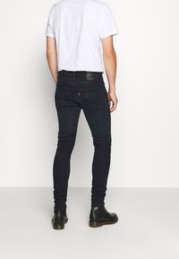 Svarta slim fit-jeans i denim med medelhög midja, fem fickor och en läderetikett på baksidan av midjan. Kombinera med svarta stövlar.