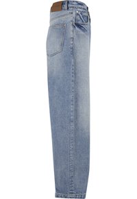 Vaqueros de denim azul claro mostrados de lado con pierna recta, bolsillo trasero visible y parche de marca de cuero en la cinturilla.