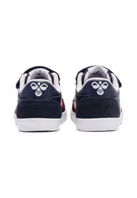 Granatowe zamszowe sneakersy z białą podeszwą, z gładką panelem pięty, czerwonymi akcentami i logo z tyłu w pobliżu kołnierza.