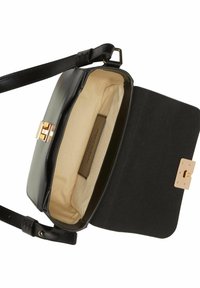 Sac à main en cuir noir avec une forme structurée, fermoir en métal doré et doublure beige. Dispose d'une sangle réglable et d'une poche intérieure.