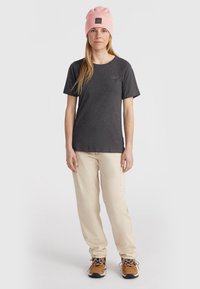 Donkergrijze t-shirt, beige cargobroek, roze beanie met patch, bruin-witte schoenen. Ontspannen pasvorm en zachte textuur voor comfort.