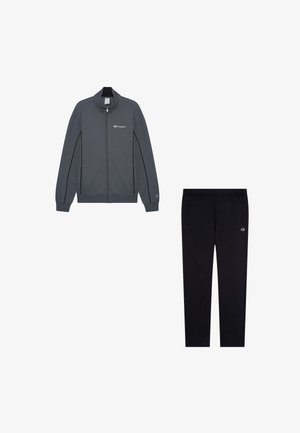 Giacca grigia con zip, accenti neri e logo sul petto, abbinata a pantaloni neri con vita elastica e tasche laterali, anch'essi con logo.