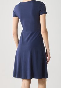 Short-sleeve, navy blue dress made of soft fabric, featuring a fitted waist and flared skirt, with a round neckline and smooth texture.