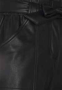Shorts en cuir noir avec une texture lisse, des poches latérales et un détail de ceinture nouée à la taille avec de subtils accents de couture.