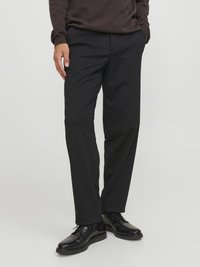 Pantaloni neri realizzati in tessuto leggero con taglio dritto, dotati di tasche laterali e texture liscia, abbinati a scarpe nere.