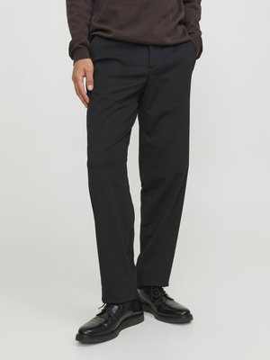 Pantaloni neri realizzati in tessuto leggero con taglio dritto, dotati di tasche laterali e texture liscia, abbinati a scarpe nere.