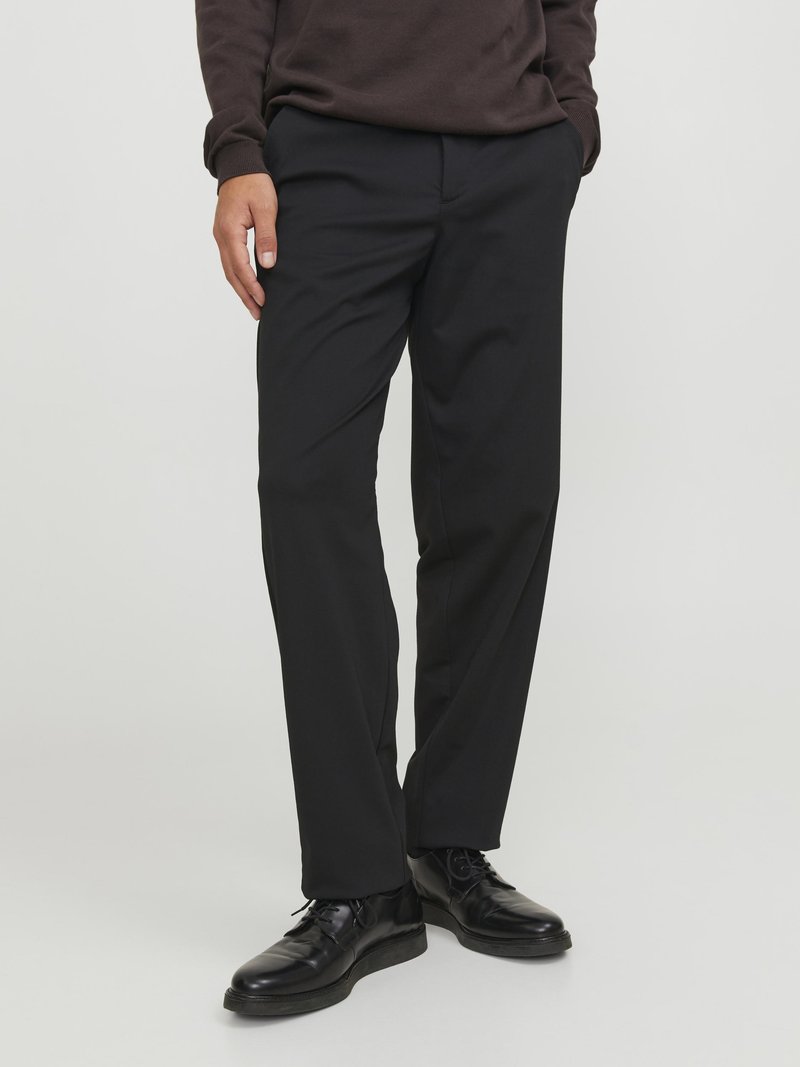 Pantaloni neri realizzati in tessuto leggero con taglio dritto, dotati di tasche laterali e texture liscia, abbinati a scarpe nere.