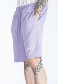 Paarse katoenen shorts met een elastische tailleband en trekkoord. Voorzien van zijzakken en het woord "MULTIPLY" in het wit op de zoom.