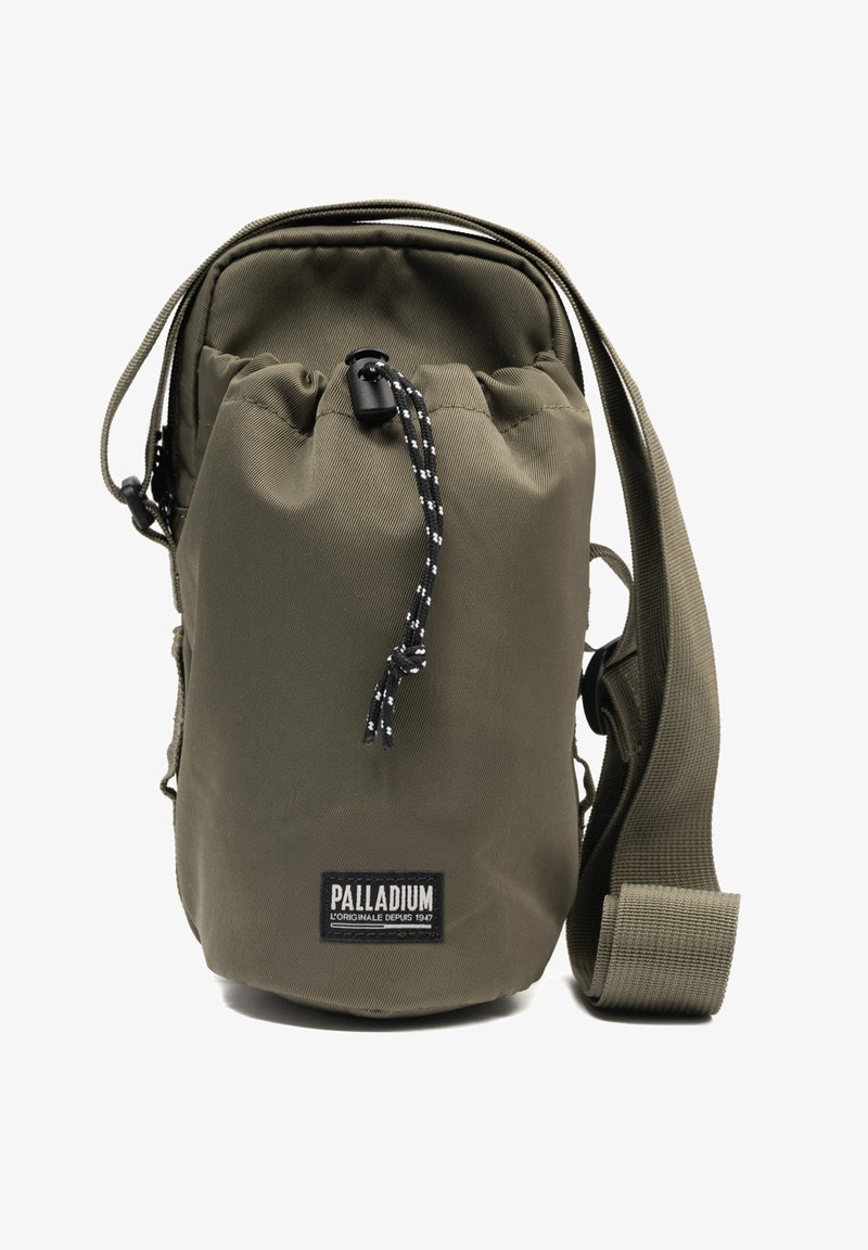Petit sac bandoulière vert olive avec sangle ajustable, fermeture à cordon et étiquette de la marque Palladium sur le devant.