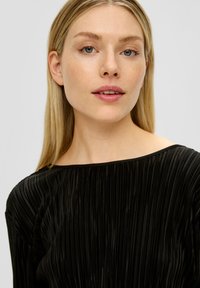 Zwarte geplooide jurk met een breed, bootneck decolleté, gemaakt van textuurstof, met verticale lijnen en een gladde afwerking.