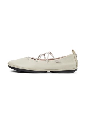 Ballerine beige chiaro con sottili cinturini incrociati e suola in gomma nera, mostrate di lato su uno sfondo bianco.