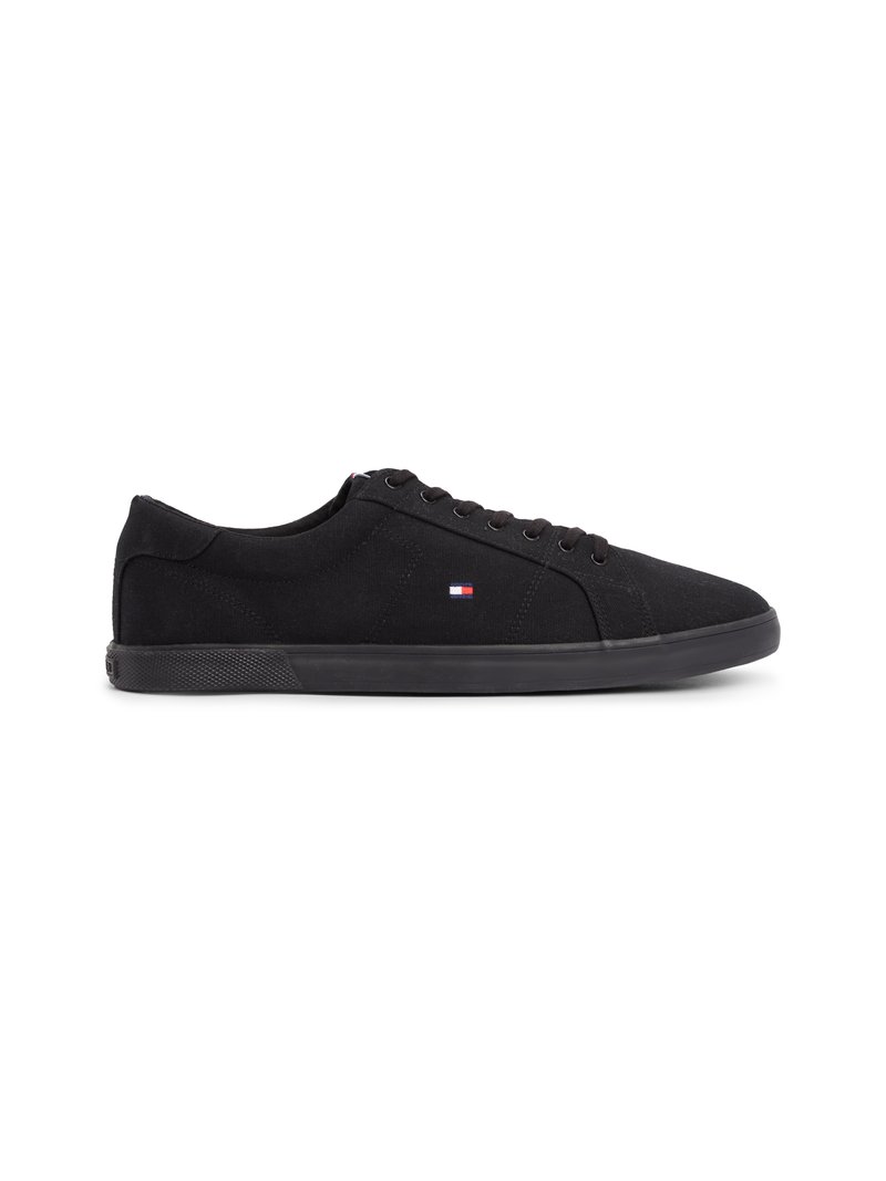 Black canvas sneakers with a textured upper, round toe, and flat rubber sole. Features six eyelets and a small tri-color logo near the tongue.