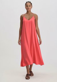 Koraalkleurige maxi-jurk met dunne verstelbare bandjes, een V-halsontwerp en een losse, vloeiende silhoeët. Zachte stof valt soepel tot op de enkels.