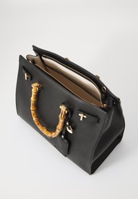 Zwarte leren handtas met een bamboe handvat, gouden hardware accenten en een ritsopening. Het interieur heeft een beige voering en vakken.