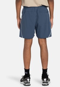 Blaue Sportshorts aus atmungsaktivem Material, mit elastischem Bund und weißen seitlichen Streifen. Enthält eine Rückentasche für Stauraum.