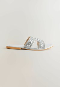 Sandale plate argentée à bout ouvert, dotée d'une large bride brodée et d'une semelle beige.