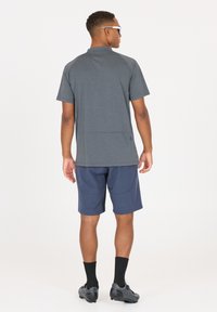Herrarnas sportoutfit som består av en mörkgrå, strukturerad t-shirt med kort ärm och marinblå shorts. T-shirten har en avslappnad passform och en bakfickdetalj.