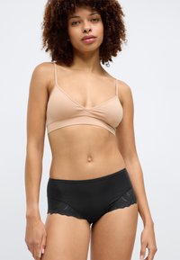 Nøgen bralette i blødt stof med V-udskæring og tynde stropper. Sorte højtaljede trusser med blonder trim på siderne.