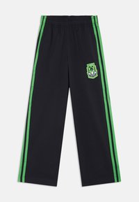 Black athletic pants with green side stripes and an embroidered logo patch. Features an elastic waistband and a straight-leg design.