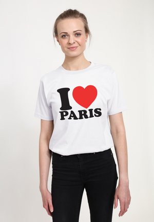 Biała bawełniana koszulka z napisem "I ❤️ PARYŻ" w czarnym kolorze i czerwoną sercem, noszona z czarnymi dżinsami.