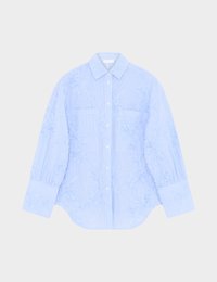 Ανοιχτό μπλε μακρυμάνικο πουκάμισο με κεντήματα λουλουδιών, δύο τσέπες στο στήθος, φαρδιά μανσέτα και κλασικό γιακά σε λευκό φόντο.