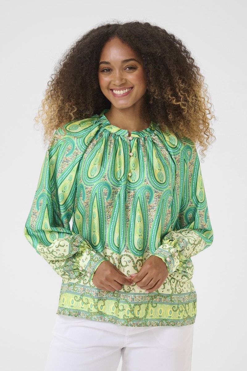 Blusa verde con motivo paisley, dotata di scollo arricciato, maniche lunghe e dettagli con bottoni. Il tessuto presenta intricate fantasie floreali e geometriche.