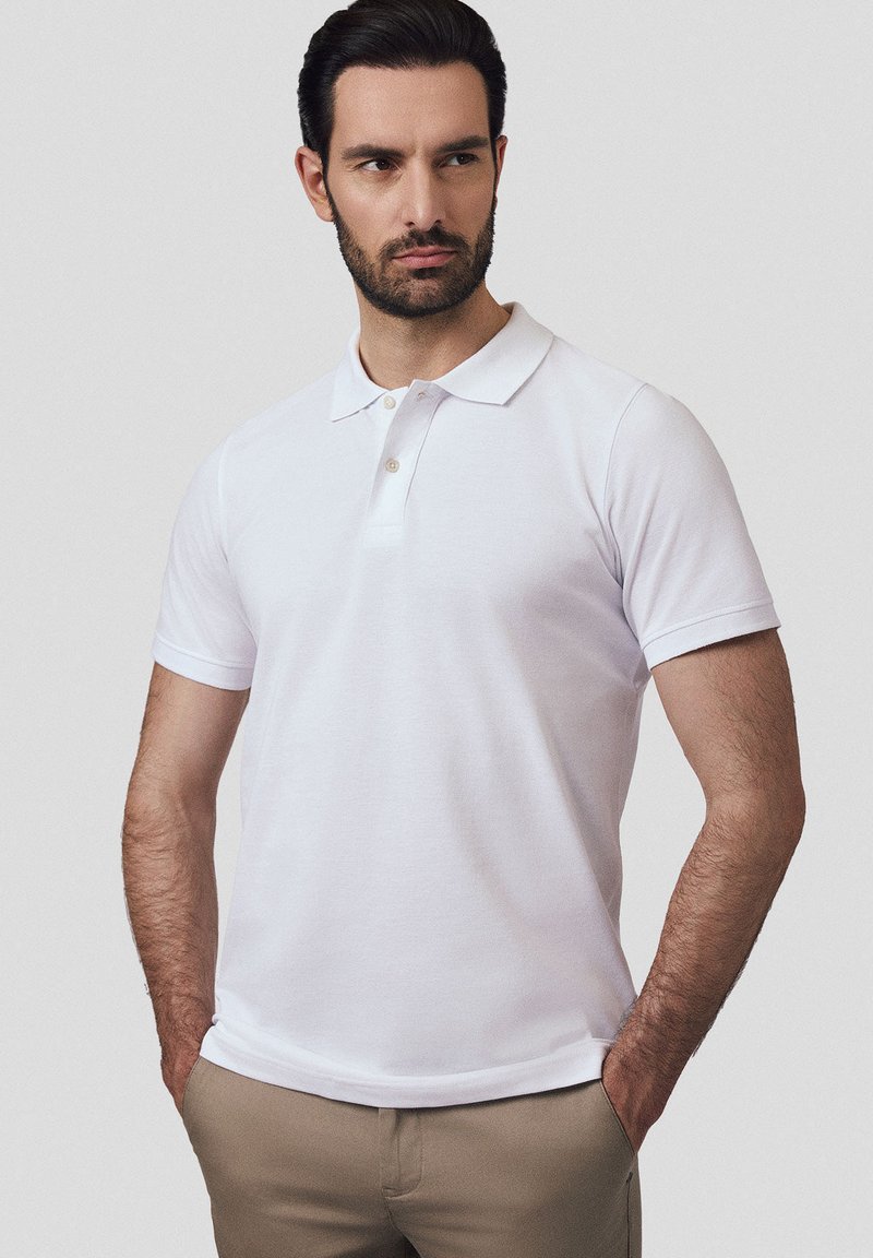 Biała koszulka polo z krótkim rękawem, wykonana z bawełny, z klasycznym kołnierzykiem i zapięciem na trzy guziki. Gładka faktura i dopasowany krój.