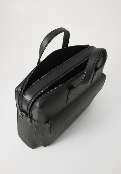 Black leather bag with two zippered compartments, structured shape, flat handles, and a front pocket. Smooth texture with minimal hardware.