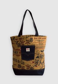Torba tote z kanwy w brązowych i niebieskich kolorach, z akcentami z denimu, nadrukowanymi grafikami oraz metką Levis. Podwójne czarne uchwyty.