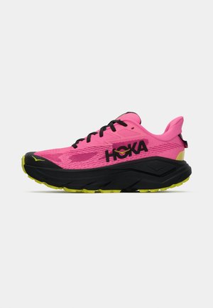 Kirev roosa jooksujalanõud musta tallaga ja nööridega, kollaste aktsentidega ning "HOKA" logoga küljel, valge tausta ees.